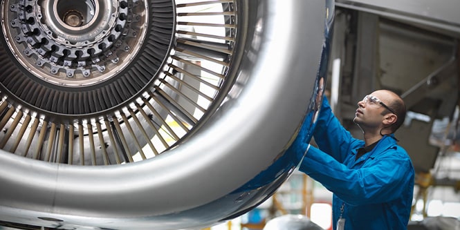 Person inspecting an aircraft engine.

