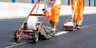 People applying road marking tape to a new road
