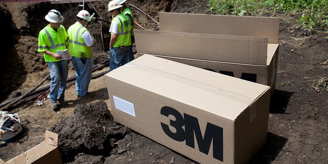 Boxes of 3M product on the ground near workers
