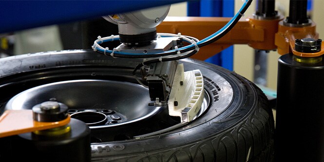 Automotive tire and wheel on machine with 3M wheel weights being applied
