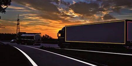 Truck on a dark road with conspicuity markings.
