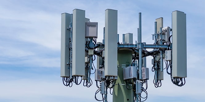 Close-up of the top of an antenna tower with blue skies behind it.
