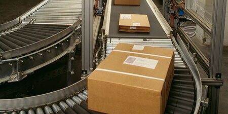 Three packages ready for shipping on a conveyor belt.
