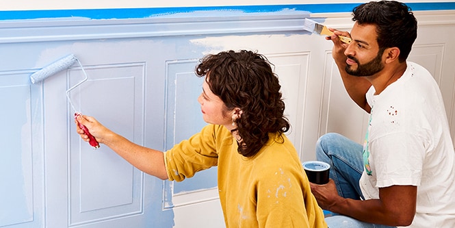 A couple painting a wall using Scotch® Masking Tape.
