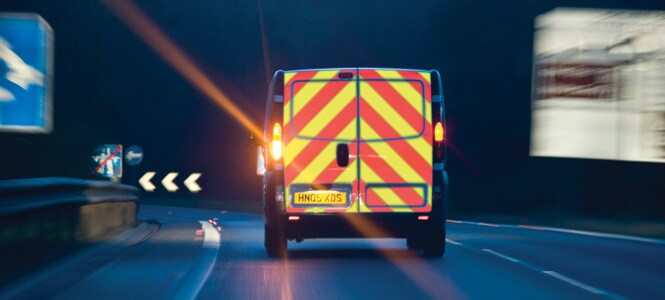 Van with rear chevron markings driving on a dark road
