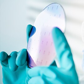 Individual holding up semiconductor wafer to the light.