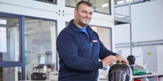 Men working holding a welding helmet
