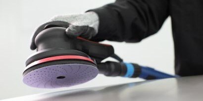 Technician sanding a damaged car panel
