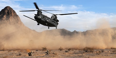military helicopter landing with dust flying

