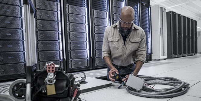 worker in datacenter installing electrical conduit under the floor
