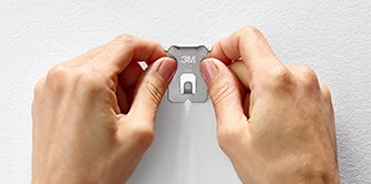 Two hands showing how the 3M CLAW™ Heavyweight Picture Hanger works
