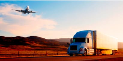 commercial truck on a highway with an aeroplane flying overhead
