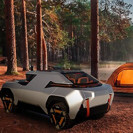 A futuristic electric grey coupe at a campsite surrounded by forest