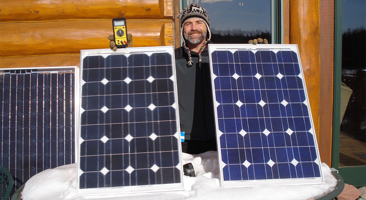 3M scientist Tim Hebrink holding the solar panels that have helped him generate about 80 percent of his home’s energy