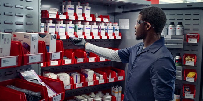 A technician scans the product label of a bin in a cabinet.
