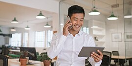 Person holding a phone and tablet smiling