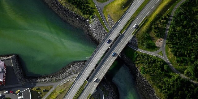 Ariel view of electrified vehicles with range extending capabilities crossing a bridge on a rural highway.