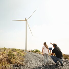 Man pointing at a wind turbine with little girl looking at it.